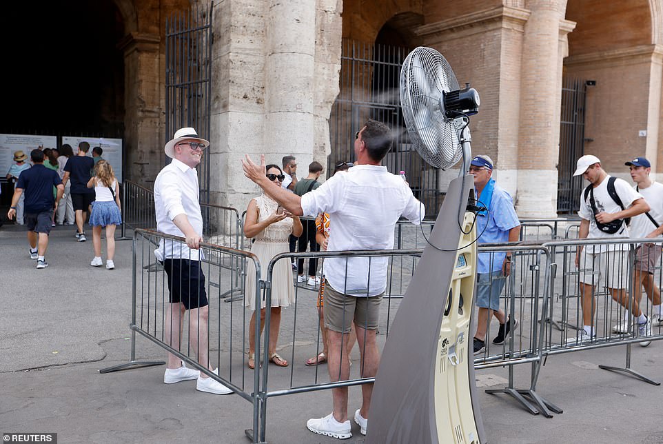 A man stands in front of a fan before entering the Colosseum in Rome during a heat wave across Italy on Monday