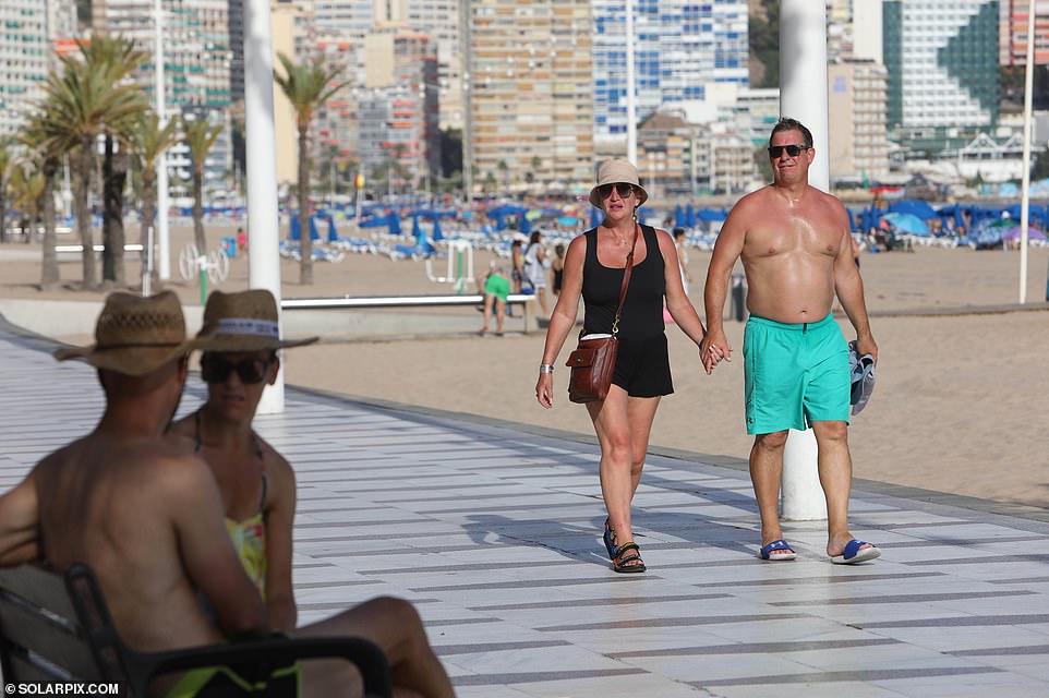 British tourists are braving the extreme heat to sunbathe on beaches and walk along the promenades across Benidorm in Spain on Monday