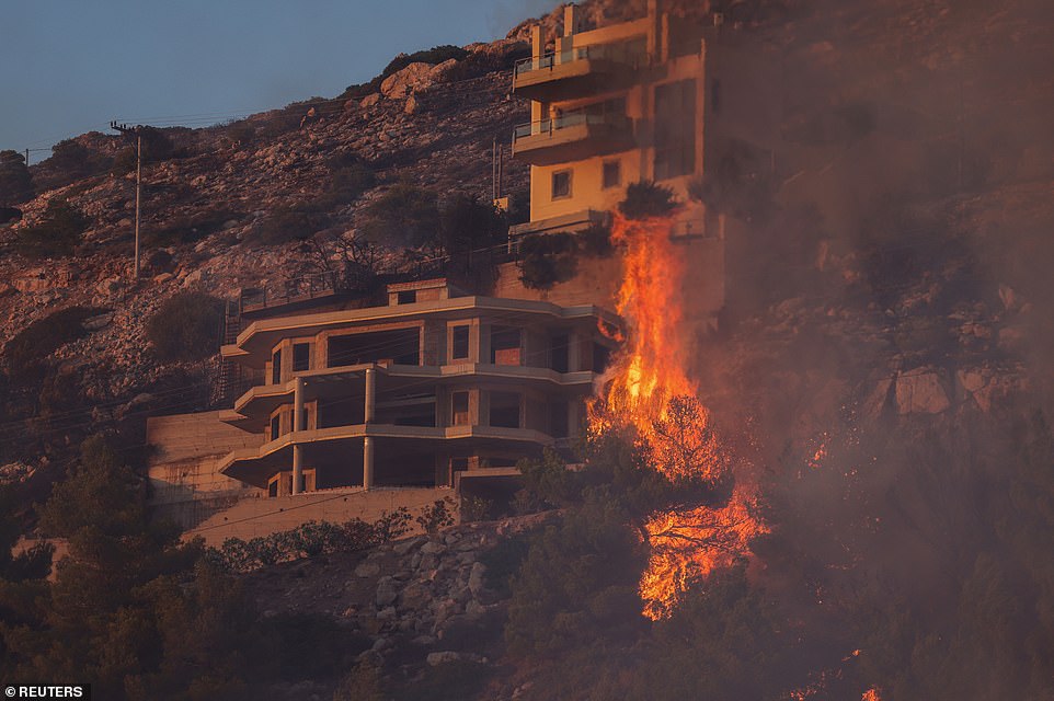Flames approach a house as a wildfire burns in Saronida, near Athens, Greece, on Tuesday