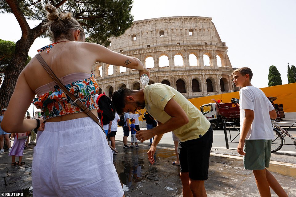 A woman pours water on a man near the Colosseum, during a heatwave across Italy, as temperatures are expected to rise further in the coming days, in Rome, Italy, on Tuesday