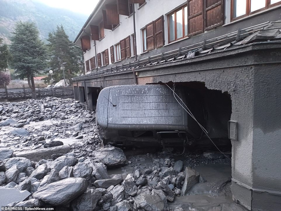 Further video shows a thick wall of mud coursing down the river banks that pass through the Alpine town, blanketing cars with debris