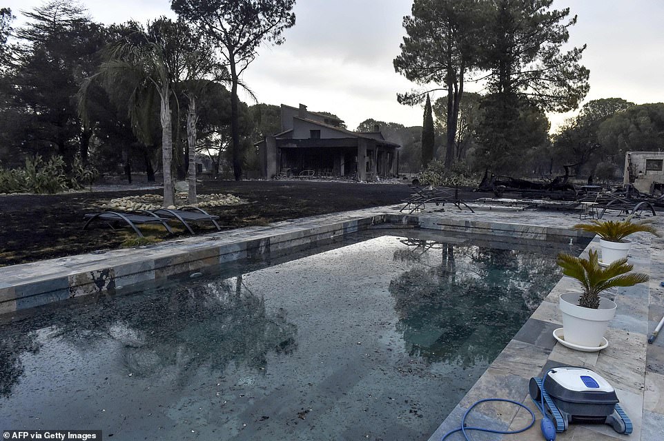 The smouldering remains of a house are seen behind a pool in the aftermath of the fire that ravaged the commune of Saint-Andre in Pyrenees-Orientales on Tuesday