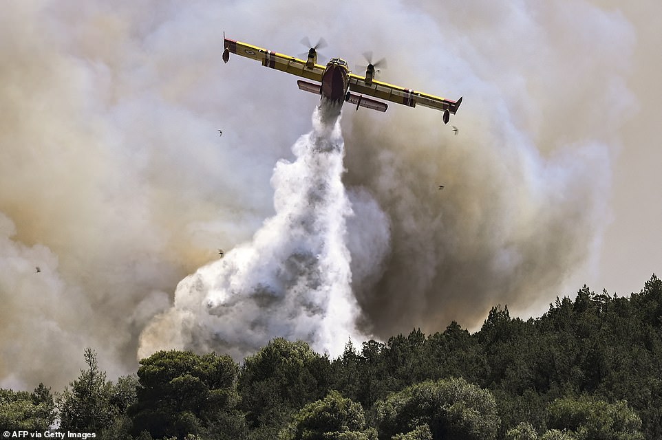 A Canadair firefighting plane sprays water during a fire in Dervenochoria, north-west of Athens, on July 19