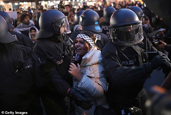 BERLIN, GERMANY - OCTOBER 18: Riot police detain a young woman at a gathering of pro-Palestinian demonstrators on Sonnenallee in Arab-heavy Neukoelln district on October 18, 2023 in Berlin, Germany. Several hundred protesters defied a ban on the protest to gather and shout "Free, free Palestine!" and "Allahu Akbar." The current conflict between Hamas and Israel is continuing to claim lives daily, especially since yesterday's explosion at a hospital in Gaza that reportedly left hundreds dead. An Israeli invasion of Gaza is possibly imminent. (Photo by Sean Gallup/Getty Images)