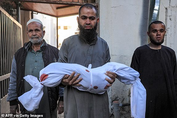 EDITORS NOTE: Graphic content / The uncle of a Palestinian girl from the Duheir family, who was killed in an Israeli air strike carries her body at a hospital in Rafah in the southern Gaza Strip on October 19, 2023. Thousands of people, both Israeli and Palestinians have died since October 7, 2023, after Palestinian Hamas militants based in the Gaza Strip, entered southern Israel in a surprise attack leading Israel to declare war on Hamas in Gaza on October 8. (Photo by SAID KHATIB / AFP) (Photo by SAID KHATIB/AFP via Getty Images)