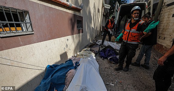 epa10927040 Palestinian civil defense workers stand next to the bodies of some members of the Saqallah family following an Israeli air strike in the south west of Gaza City, 19 October 2023. More than 30 family members were killed in an Israeli air strike. According to Palestinian health authorities and Israel Defence Forces (IDF), more than 3,500 Palestinians and 1,400 Israelis have been killed since 07 October, when Hamas militants launched an attack against Israel from the Gaza Strip, leading to Israel's response. Israel has warned all citizens of the northern Gaza Strip to move to the south ahead of an expected invasion.  EPA/MOHAMMED SABER