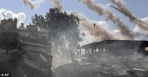 Qassam rockets fly over destroyed buildings following Israeli airstrikes on Gaza City, central Gaza Strip, Thursday, Oct. 19, 2023. (AP Photo/Mohammed Dahman)
