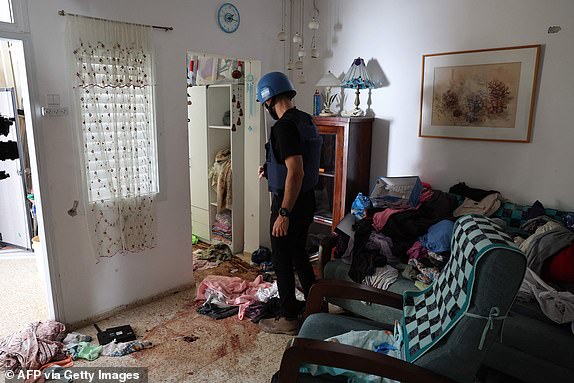 A foreign journalist checks blood stains on the floor of a house inside the kibbutz Nir Oz along the border with the Gaza Strip on October 19, 2023, following the October 7 attack by Hamas militants. Thousands of people, both Israeli and Palestinians have died since October 7, 2023, after Palestinian Hamas militants based in the Gaza Strip, entered southern Israel in a surprise attack leading Israel to declare war on Hamas in Gaza on October 8. (Photo by JACK GUEZ / AFP) (Photo by JACK GUEZ/AFP via Getty Images)