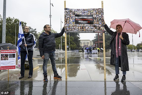 Protesters hold banners with hostages' pictures during a gathering next to the European headquarters of the United Nations in Geneva, Switzerland, Thursday, October 19, 2023. (Martial Trezzini/Keystone via AP)