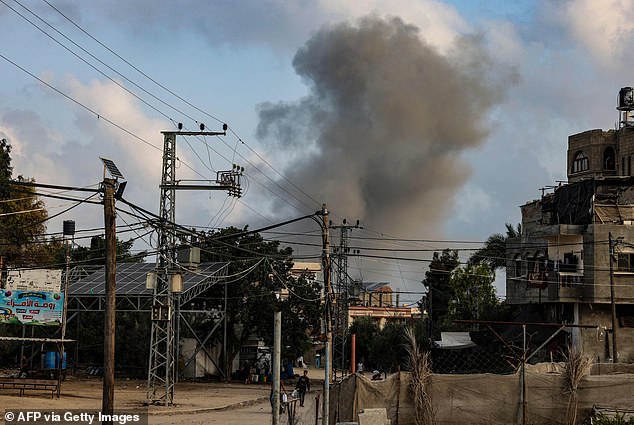 A young man transports a bag of food as smoke rises from buildings behind him during an Israeli strike in Rafah in the southern Gaza Strip October 22, 2023