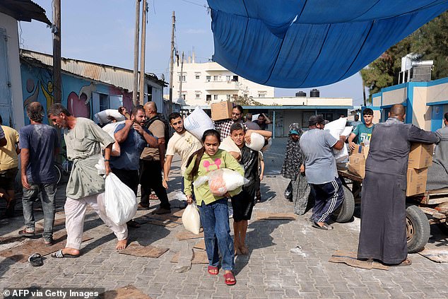Palestinians carry food aid from a UN-run supply centre on Saturday morning as deliveries were made from the southern border with Egypt