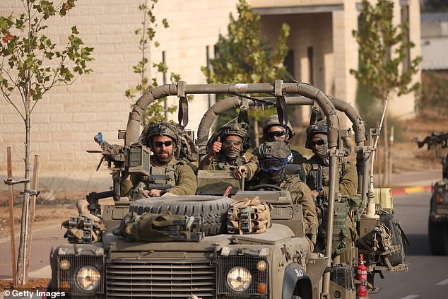 Israeli troops give a thumbs-up to a photographer as they pass through the border town of Sderot, less than a kilometre from Gaza