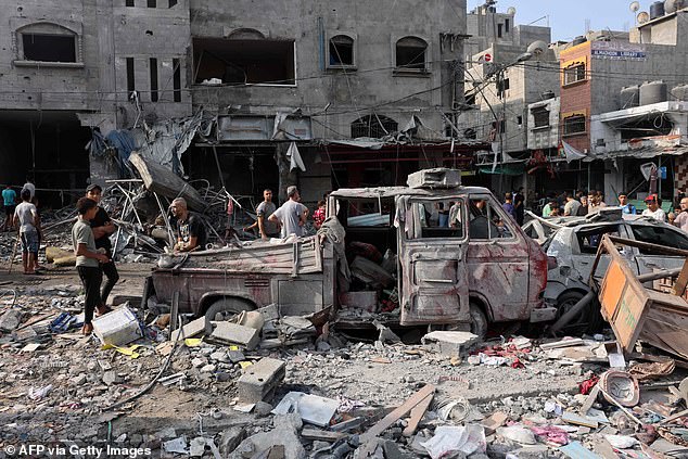 People gather amid the destruction around the Al-Shatee camp on Saturday after the latest round of bombardments
