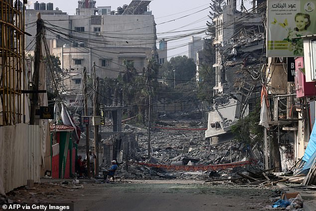 A man sits in front of devastated buildings and rubble in the streets of Gaza City on Saturday after fierce overnight bombardment carried out by Israel