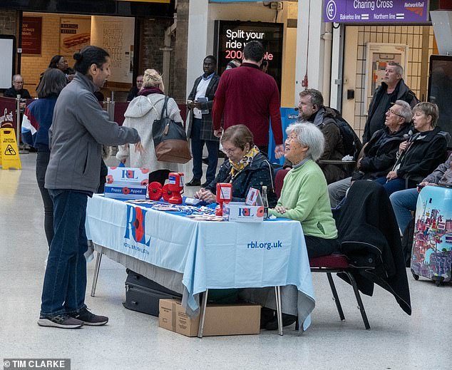 Two volunteers speak to a commuter at Charing Cross Station in central London today