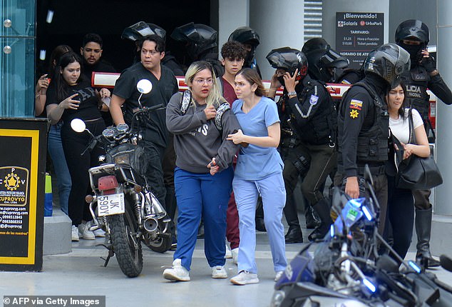 People are helped out of the premises of Ecuador's TC television channel after unidentified gunmen burst into the state-owned television studio live on air on Tuesday