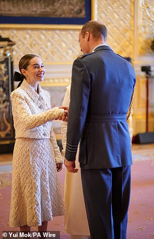 Emilia Clarke beams as she shakes hands with the Prince of Wales at Windsor Castle today