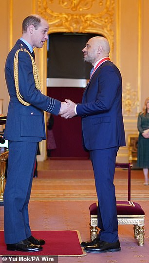 Sajid Javid shakes hands with Prince William and smiles as he is awarded a knighthood at Windsor Castle