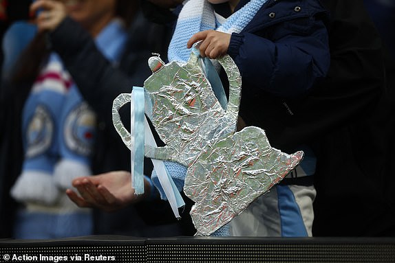 Soccer Football - FA Cup - Quarter Final - Manchester City v Newcastle United - Etihad Stadium, Manchester, Britain - March 16, 2024 A tin foil cut out of the FA Cup trophy is held by a Manchester City fan before the match Action Images via Reuters/Lee Smith