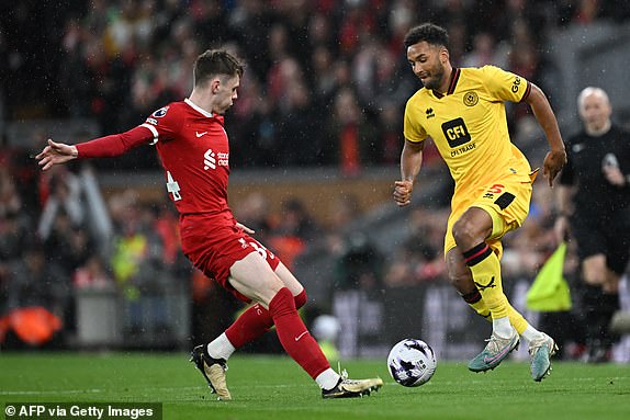 Liverpool's Northern Irish defender #84 Conor Bradley (L) fights for the ball with Sheffield United's US defender #05 Auston Trusty during the English Premier League football match between Liverpool and Sheffield United at Anfield in Liverpool, north west England on April 4, 2024. (Photo by Paul ELLIS / AFP) / RESTRICTED TO EDITORIAL USE. No use with unauthorized audio, video, data, fixture lists, club/league logos or 'live' services. Online in-match use limited to 120 images. An additional 40 images may be used in extra time. No video emulation. Social media in-match use limited to 120 images. An additional 40 images may be used in extra time. No use in betting publications, games or single club/league/player publications. /  (Photo by PAUL ELLIS/AFP via Getty Images)